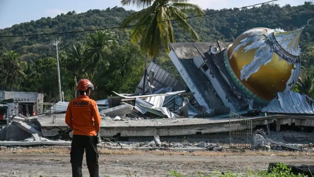 Petugas Basarnas berdiri di depan bangunan yang hancur akibat gempa bumi di Flores, Nusa Tenggara Timur.