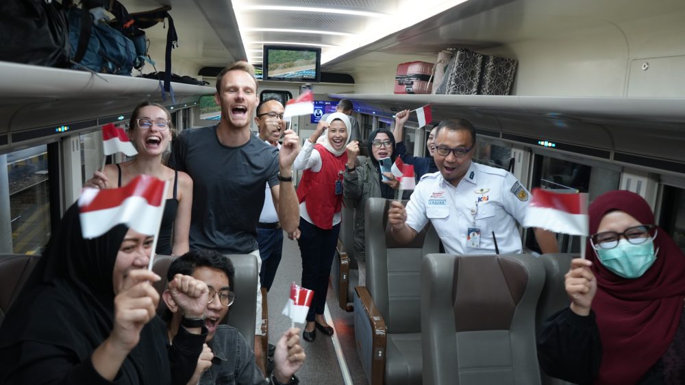 Penumpang dan petugas KAI mengibarkan bendera Merah Putih saat merayakan HUT ke-81 RI di dalam kereta api.
