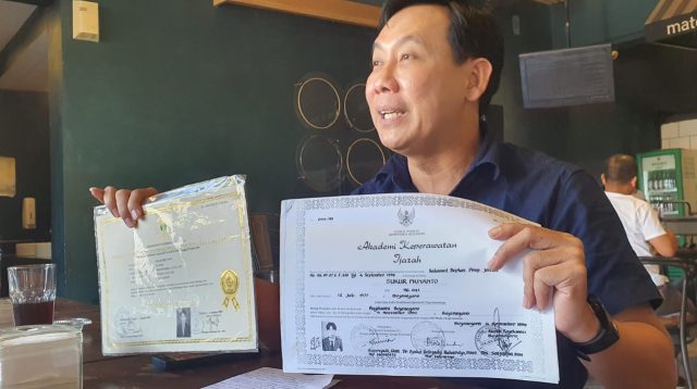 Sukur Priyanto menunjukkan dokumen riwayat pendidikan saat memberikan penjelasan terkait polemik gelar akademiknya.