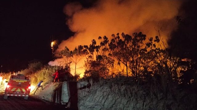 Kebakaran hutan dan lahan terjadi pada malam hari dengan kobaran api dan asap tebal, sementara petugas berada di dekat kendaraan pemadam.