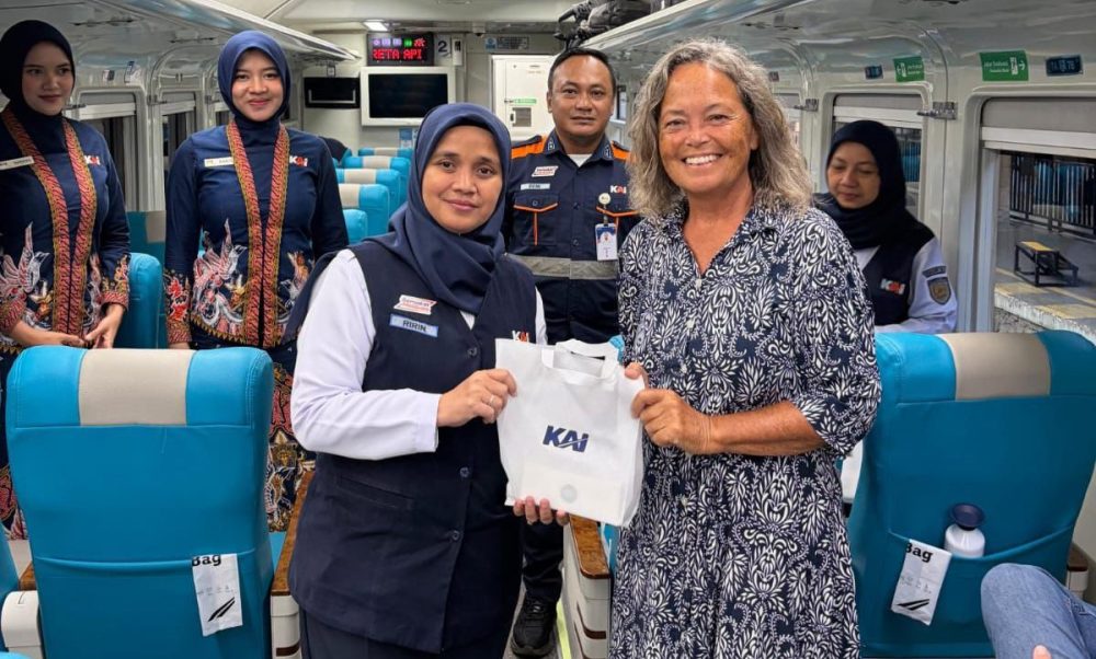 Petugas KAI Daop 8 Surabaya berfoto bersama penumpang kereta api sambil menyerahkan souvenir di dalam gerbong.