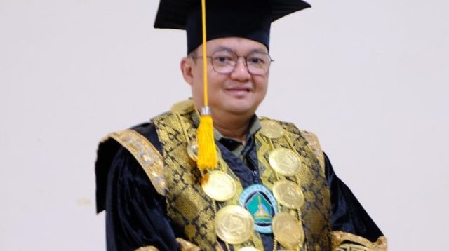 Rektor UMAHA dr. Hidayatullah, Sp.N., mengenakan toga dan busana akademik hitam berornamen emas.