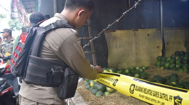 Petugas Satpol PP Surabaya memasang garis segel pada kios buah di kawasan Tambak Mayor–Tanjungsari, Rabu (28/10/2026).